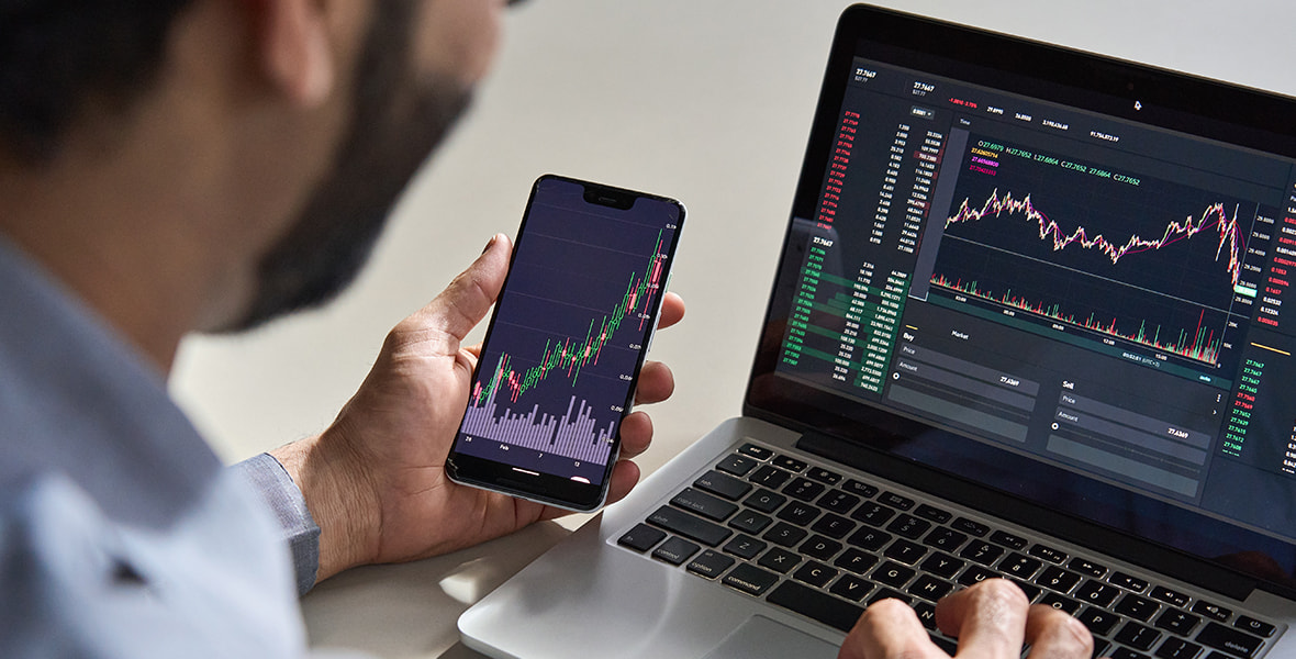 Person Holding Phone and Laptop Showing Stocks Images 