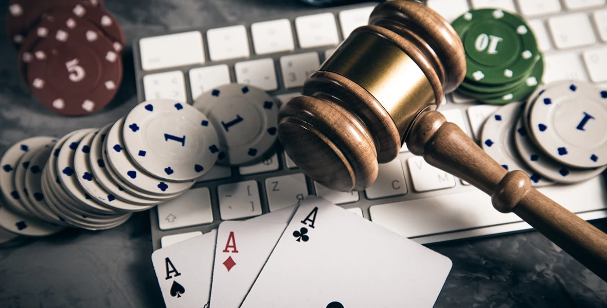 Poker chips, aces, and gavel on a keyboard, symbolizing online gambling regulations. 