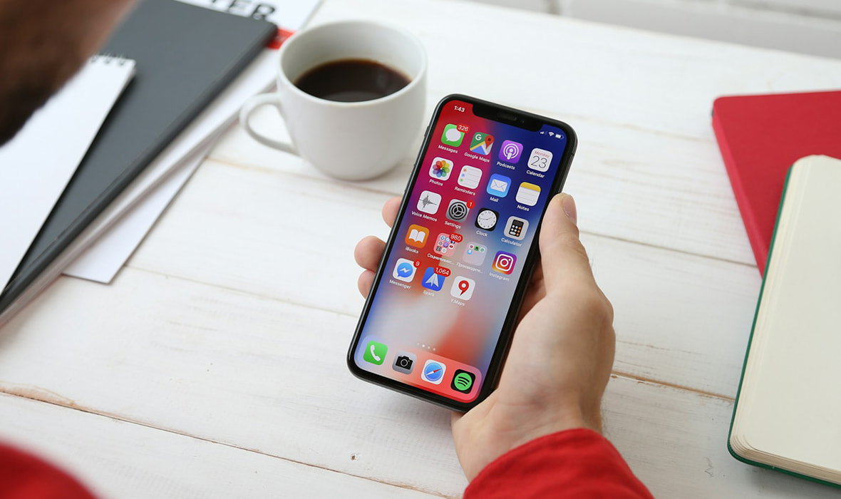 A Man Sitting on a Desk Watching a Mobile Phone 