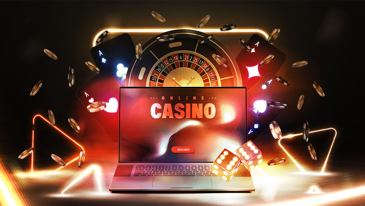 An open laptop with cards, dice, poker chips, and a roulette wheel beside it 