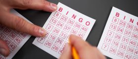 A Person's Hand Marking Numbers on a Bingo Ticket.